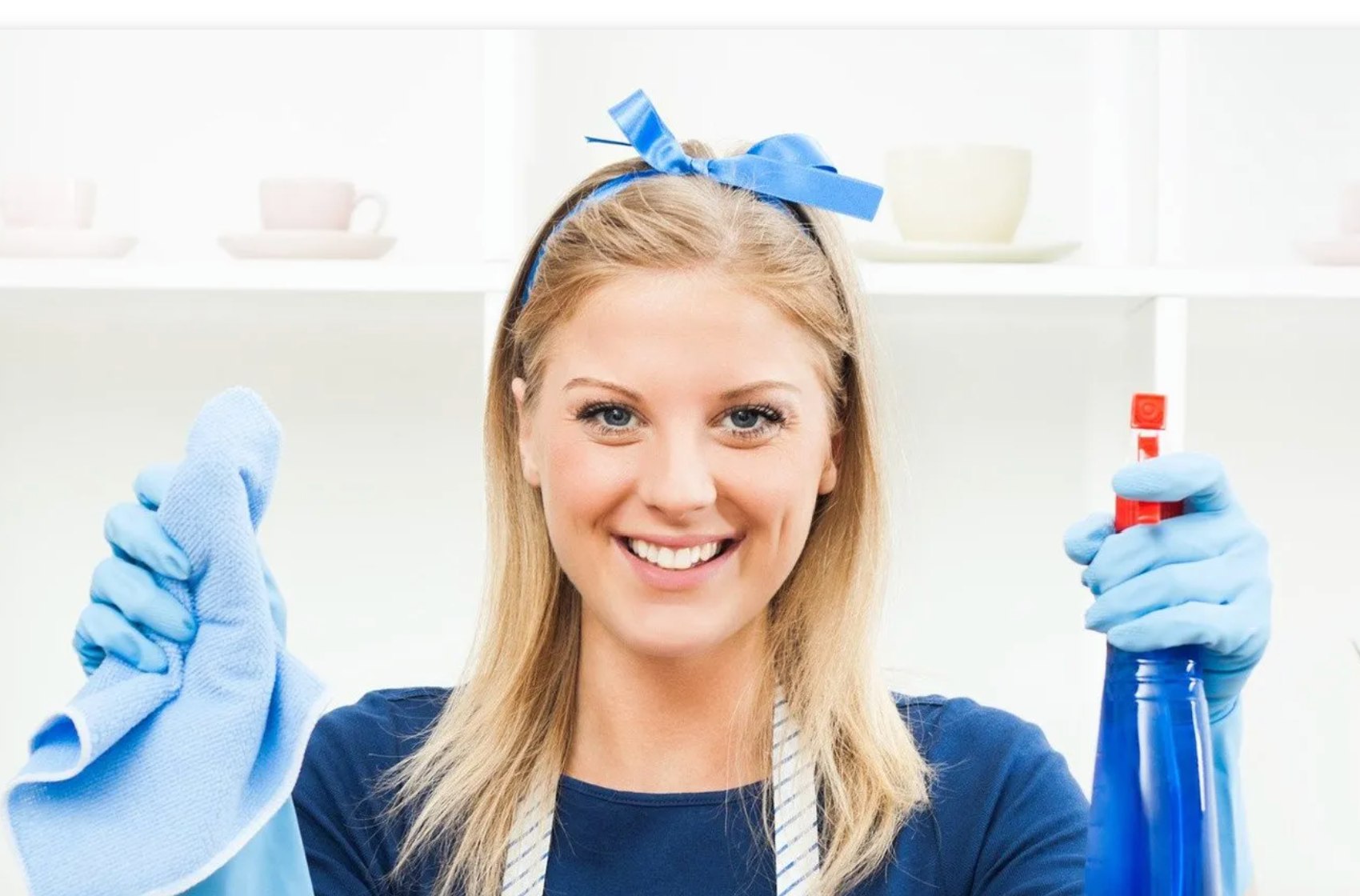 A smiling cleaner holding a spray bottle and blue cloth.