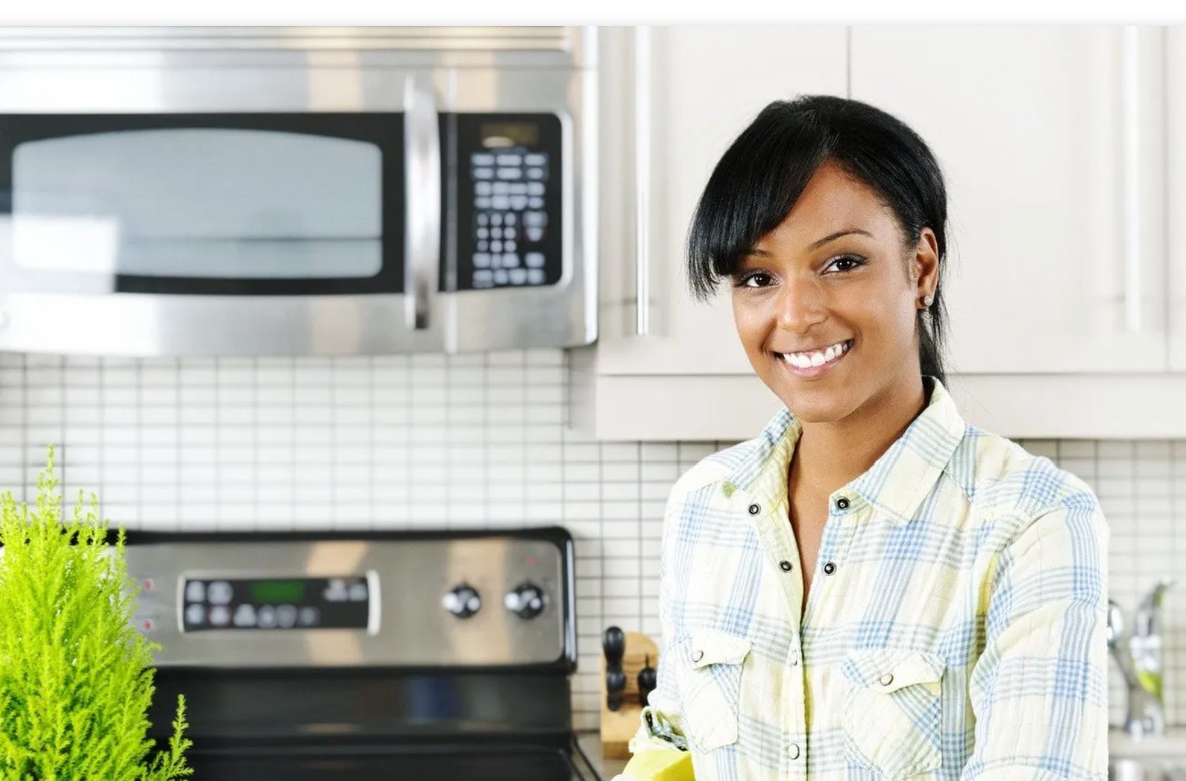 A woman wiping a kitchen counter in a bright kitchen.